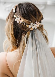 a bride wearing a veil with flowers on it's head and hair comb in her hair