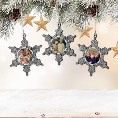 three snowflakes hanging from a christmas tree decorated with family photos and gold stars