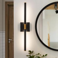 a bathroom with a round mirror on the wall and a plant in front of it