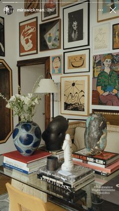 a living room filled with lots of art and decor on the wall above a glass coffee table