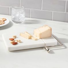 a white cutting board topped with cheese and almonds next to a plate of cookies