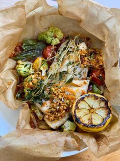 a paper bag filled with fish, vegetables and other food items on top of it