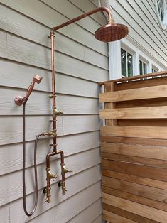 an old fashioned shower head is attached to the side of a house with wooden slats