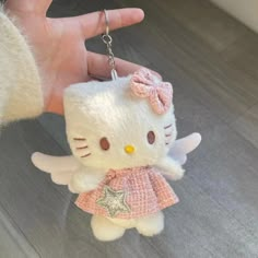 a hello kitty keychain is being held by a person with a pink dress