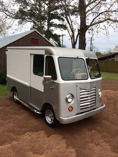 an old silver and white food truck parked in front of a barn