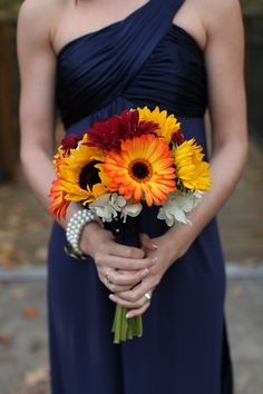 a woman in a blue dress holding a bouquet of flowers on her wedding day,