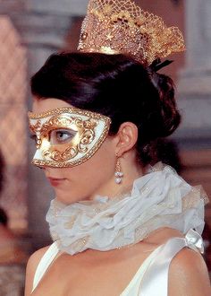 a woman wearing a gold mask and white dress