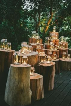 candles are lit on wooden stumps in the middle of a forest area with trees