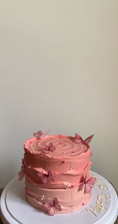 a pink frosted cake with butterflies on it