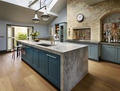 a large kitchen with blue cabinets and an island in the middle is seen from across the room