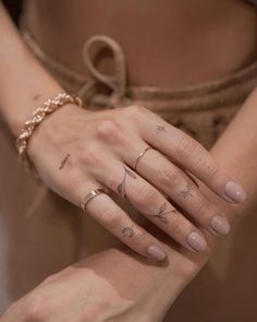 a woman's hand with three different tattoos on her left wrist and two fingers