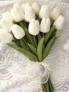 a bouquet of white tulips on a lace tablecloth