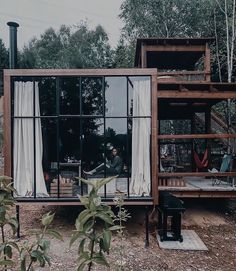 a person sitting at a table in front of a house made out of shipping containers