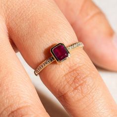 a woman's hand with a ring that has a large red stone on it