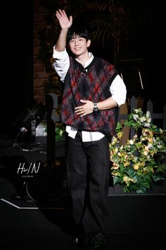 a young man waves to the crowd while standing on stage