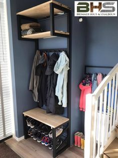 an open closet with shoes and coats hanging on the wall, next to a stair case