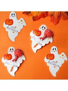 four halloween candy lollipops on an orange background