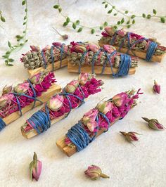 several pieces of wood with flowers on them and string wrapped around the ends, sitting on a white surface