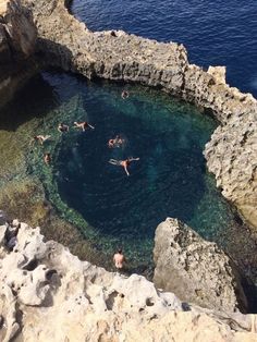 people swimming in the water near some rocks