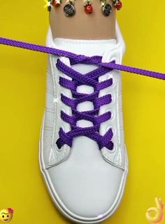 a pair of white sneakers with purple laces and beaded rings tied to them