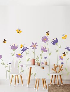 a child's room with flowers and bees painted on the wall, along with two children's chairs