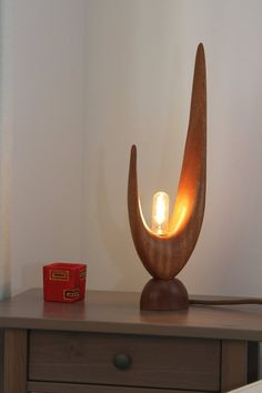 a wooden table with a lamp on it and a red box next to the light