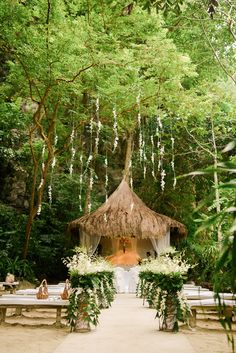 the brides are getting ready to get married at their wedding in the woods, with greenery hanging from the trees