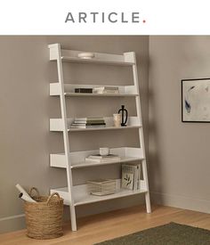 a white book shelf sitting on top of a hard wood floor next to a wall