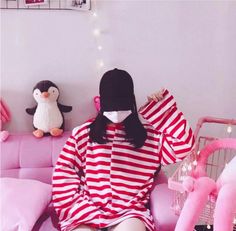 a woman sitting on top of a pink couch next to a penguin and other stuffed animals