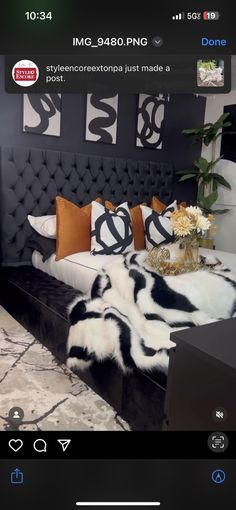 a bed with black and white fur on top of it next to a vase filled with flowers