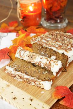 two slices of carrot cake sitting on top of a wooden cutting board next to candles