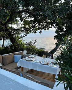 an outdoor dining area overlooking the ocean with table and chairs set up for two people