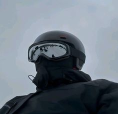 a man wearing a helmet and goggles looking up at the sky