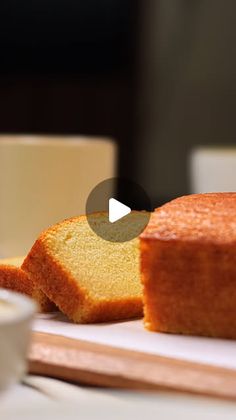 a loaf of pound cake sitting on top of a cutting board next to a cup