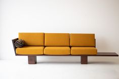 a yellow couch sitting on top of a wooden table next to a white wall in a room