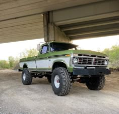 an old pick up truck parked under a bridge