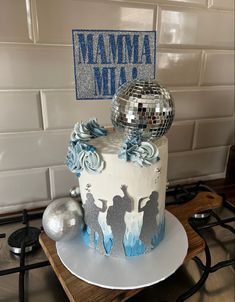 a white cake with blue decorations and a disco ball on top is sitting on a table