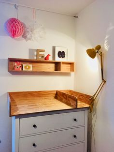 a desk with two shelves and a lamp on the wall next to it in a room