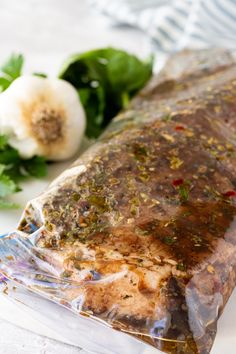 a piece of meat wrapped in plastic sitting next to some vegetables