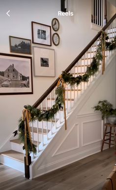 the stairs are decorated with christmas garlands and pine cones for holiday decor, along with pictures on the wall