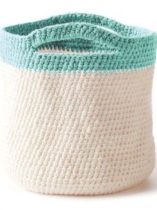 a crocheted basket with two different colors on the bottom and one white, blue, and green