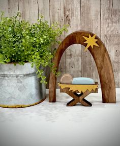 a wooden nativity scene with a potted plant next to it and an arch