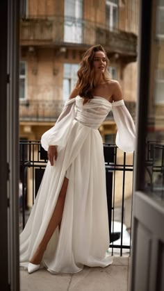 a woman in a white dress standing on a balcony