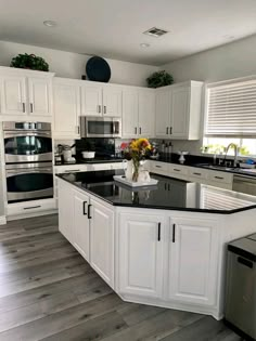 a large kitchen with white cabinets and black counter tops, stainless steel appliances and dishwasher