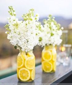 three mason jars filled with lemon slices and white flowers