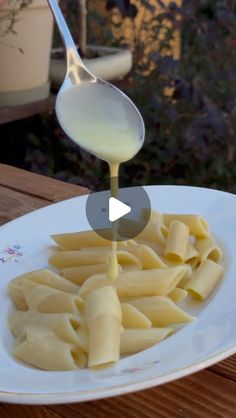 a white plate topped with pasta and sauce being drizzled on top of it