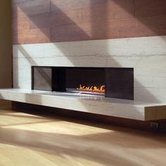 a fire place in the middle of a room with wood flooring and large windows