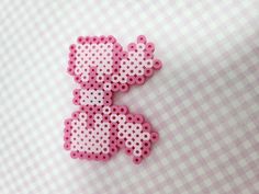 a pink and white cross stitched brooch on a checkered tablecloth background