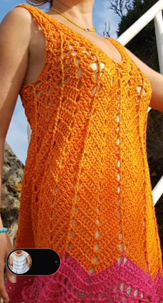 a woman in an orange and pink crochet dress standing next to a white railing