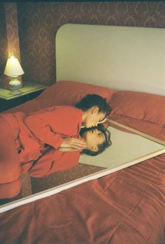 a woman laying on top of a bed in front of a mirror with her reflection